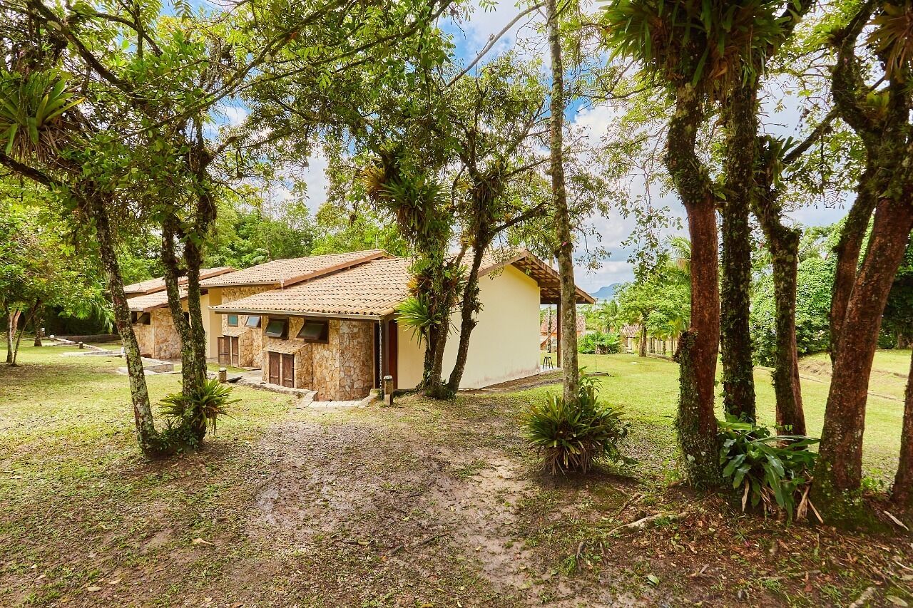 Una casa rustica con tetto in tegole, circondata da vegetazione lussureggiante e alberi.