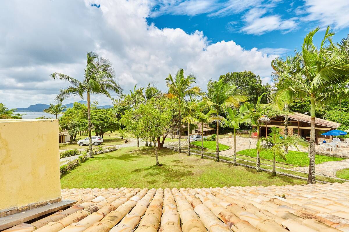 Um resort tropical com área de piscina, palmeiras e vista para o oceano.