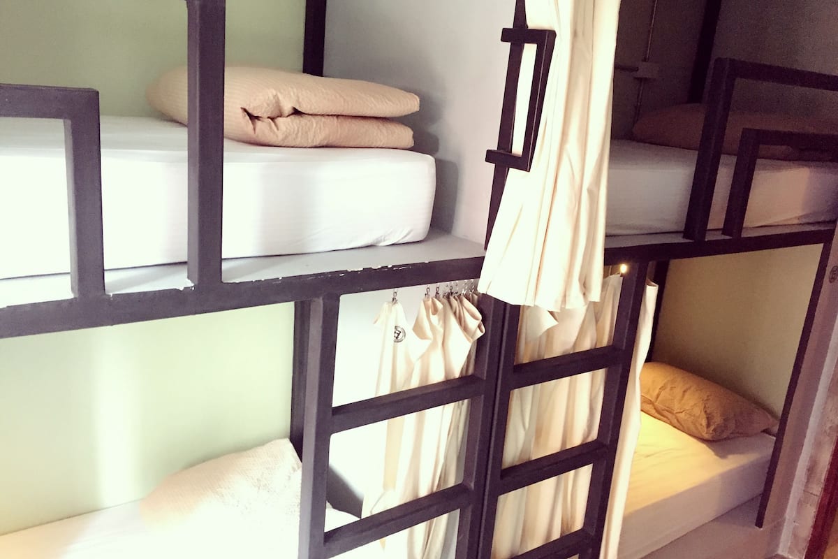 Ein Mehrbettzimmer mit Vorhang und Kissen.
