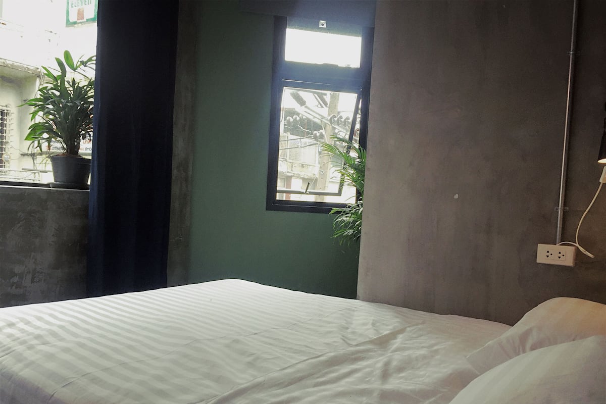 Ein Schlafzimmer mit Bett, Fenster und einer Topfpflanze.