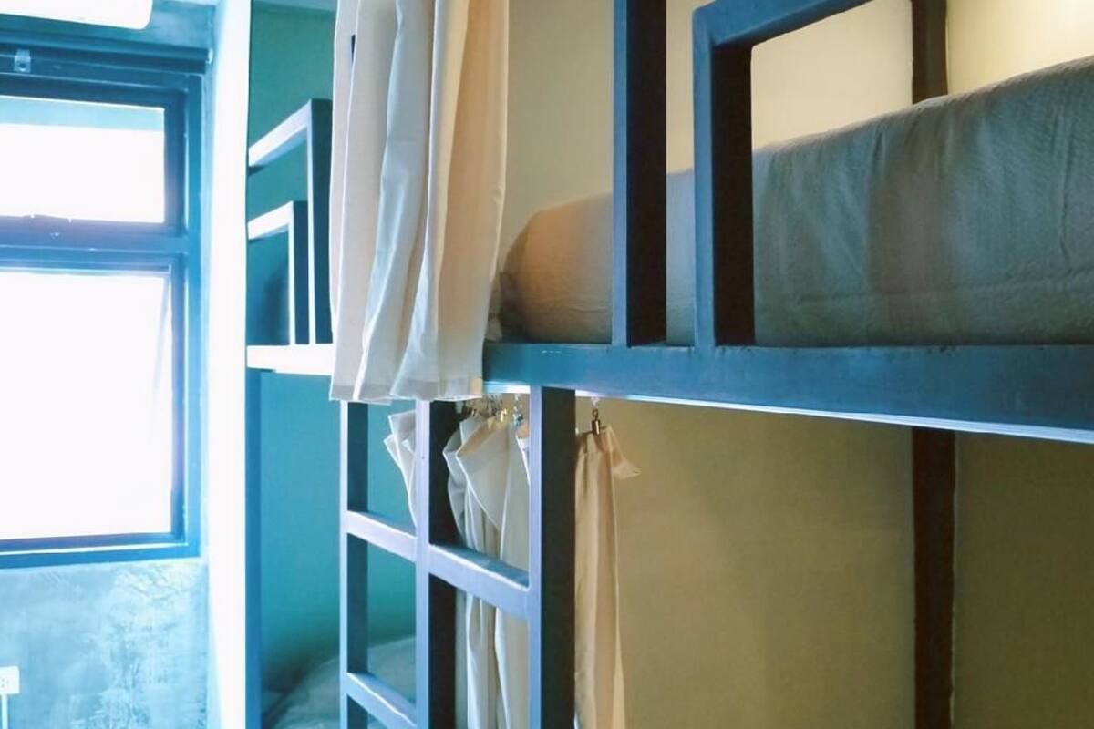 Ein Schlafzimmer mit Etagenbetten, Vorhängen, einem Fenster und einer Lampe.