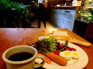 A meal with a cup of coffee, a sandwich, vegetables, and eggs on a plate. - OasisCafe&Nap - Hostel (Bangkok)
