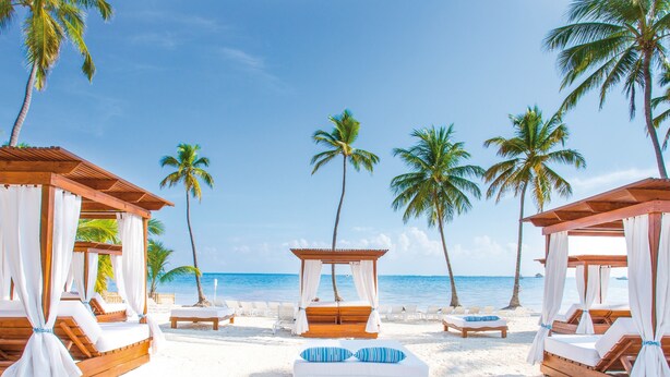 A beach resort with wooden cabanas, white beds, and palm trees. - Be Live Collection Punta Cana - Adults Only (Punta Cana)