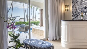 A room with a view of a pool and palm trees, a white cabinet, and a plant with purple flowers. - Be Live Collection Punta Cana - Adults Only (Punta Cana)