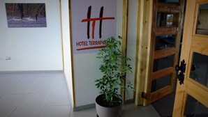 A hotel entrance with a wooden door, a potted plant, and a sign for 'Hotel Terrapuex'. - Hotel Terrapuerto (Valdivia)