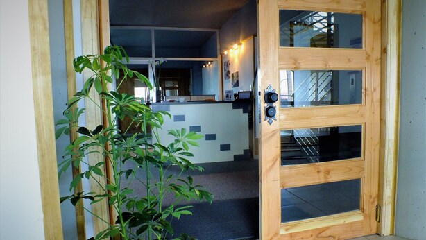 A wooden door with glass panels leading into a room with a tiled floor and a staircase. - Hotel Terrapuerto (Valdivia)