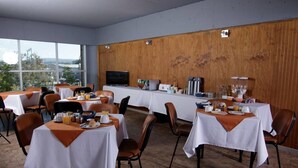 A dining area with tables set for breakfast, a television on the wall, and a view of the outdoors. - Hotel Terrapuerto (Valdivia)