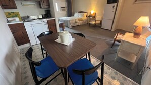 A compact kitchen with a dining area, a bed, and a small living space. - Doryman Motel (Dennis Port)