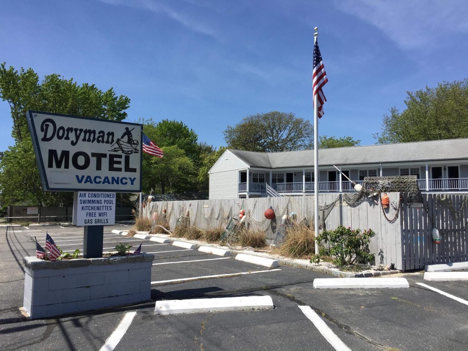 Señal de motel con servicios que incluyen aire acondicionado, piscina, cocinetas, wifi gratuito y parrillas a gas.