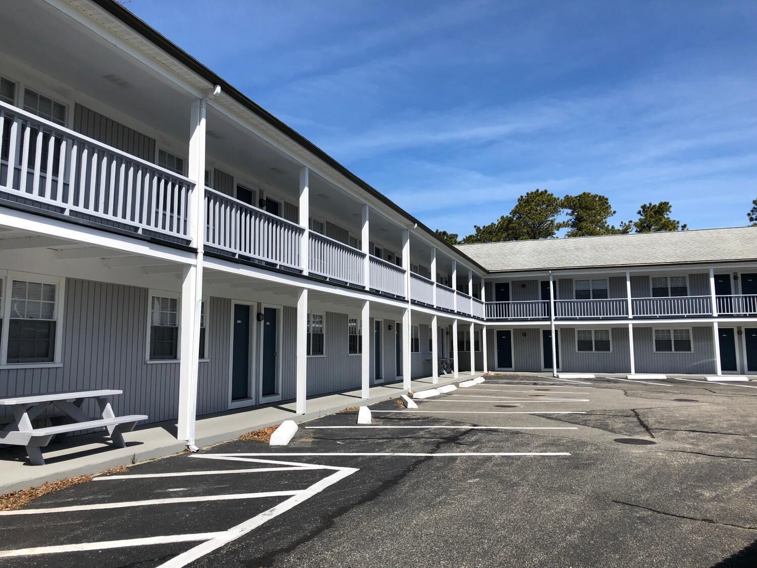A two-story motel with a covered parking area and a picnic table.