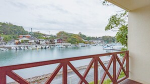 A view from a balcony overlooking a harbor with boats, houses, and a hilly landscape. - Tabist Villa Daioh Resort Iseshima (Shima)