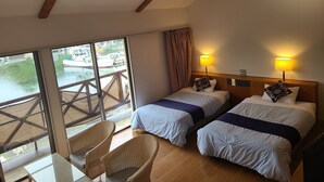 A hotel room with two beds, a window with a view of boats, a table with chairs, and a wooden ceiling. - Tabist Villa Daioh Resort Iseshima (Shima)
