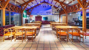 A spacious dining area with wooden tables and orange chairs, high ceilings with exposed beams, and a tiled floor. - Tabist Villa Daioh Resort Iseshima (Shima)