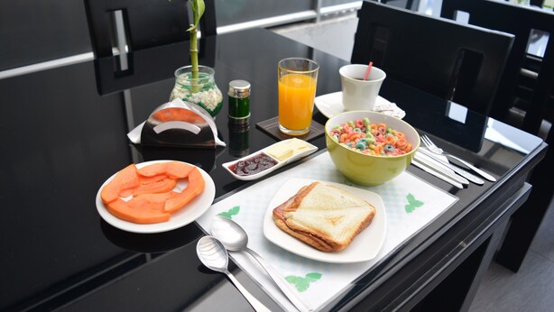 A breakfast table with plates of food, a glass of orange juice, and a bowl of cereal.