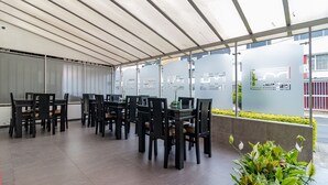 An outdoor dining area with tables and chairs, a covered roof, and decorative panels.
