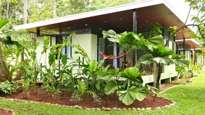 A modern building with a covered outdoor area, surrounded by lush tropical plants and a hammock. - Villas Piña - Adults Only (Cahuita)
