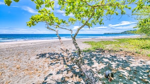 A beach with a tree in the foreground and a clear view of the ocean. - Villas Piña - Adults Only (Cahuita)