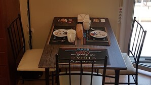 Spiseområde med et bord dækket til to personer, et ur på væggen og udsigt ud af vinduet.