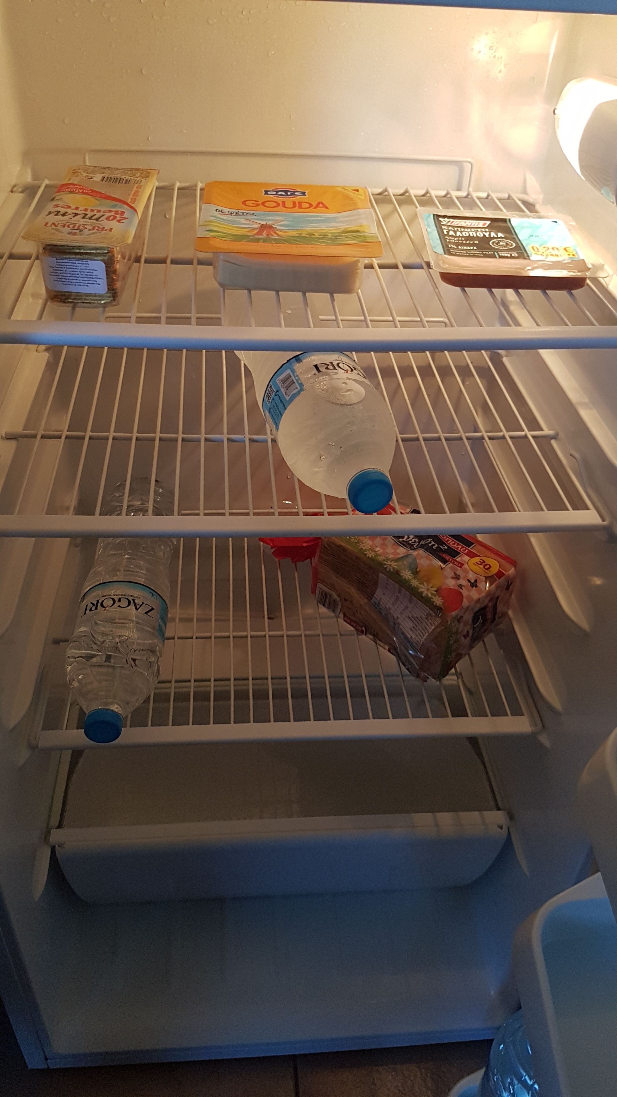 Un refrigerador con varias estantes que contiene diversos alimentos y bebidas.