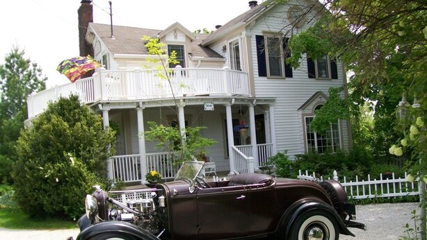 A vintage car parked in front of a house with a porch and a white picket fence. - Martha's Vineyard Bed & Breakfast (South Haven)