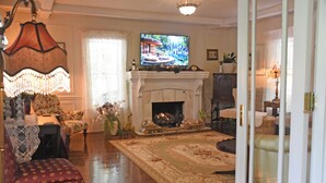 A traditional living room with a fireplace, a television, and a chandelier. - Martha's Vineyard Bed & Breakfast (South Haven)