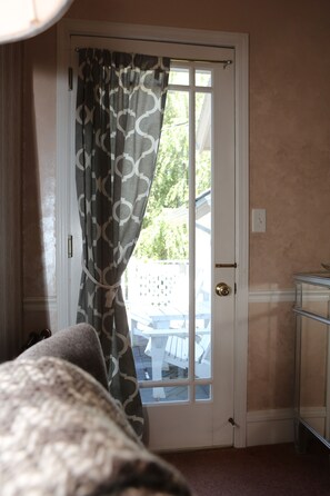 A room with a door leading to an outdoor area, a bed, and a small table with a chair. - Martha's Vineyard Bed & Breakfast (South Haven)