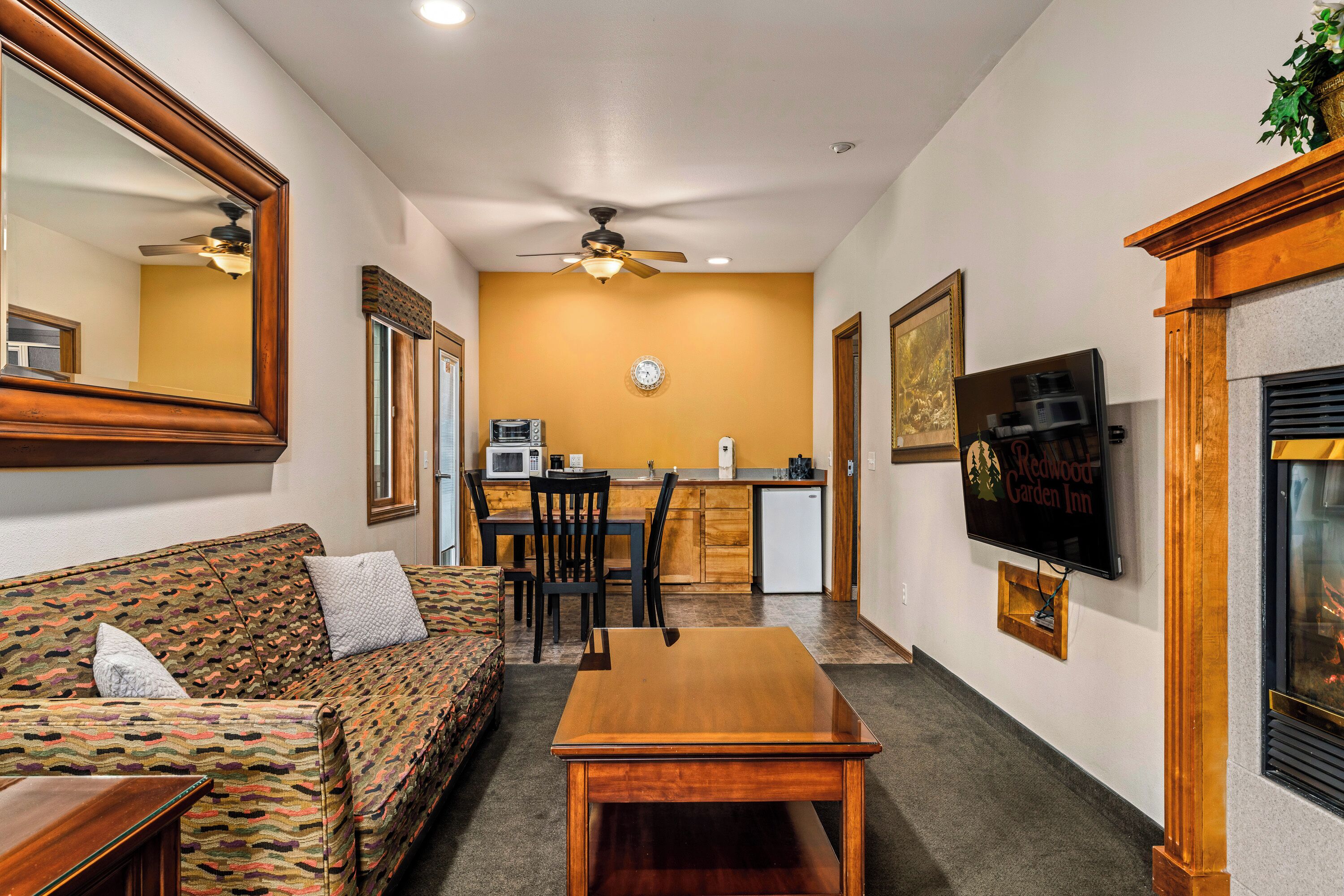 A compact living space with a sofa, a wooden table, a kitchen area with a microwave, and a fireplace.