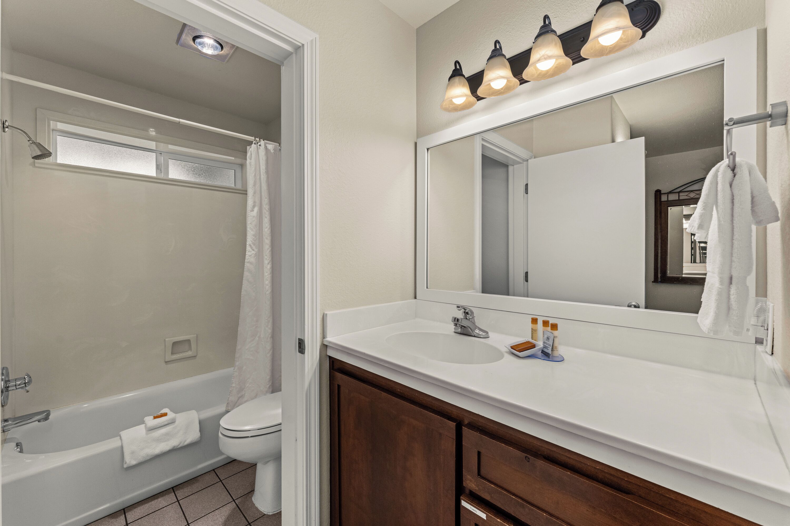 A bathroom with a bathtub, toilet, sink, and mirror.