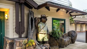 A building with a stone facade, a statue of a bear wearing a hat, and a green door. - Redwood Garden Inn (Grants Pass)