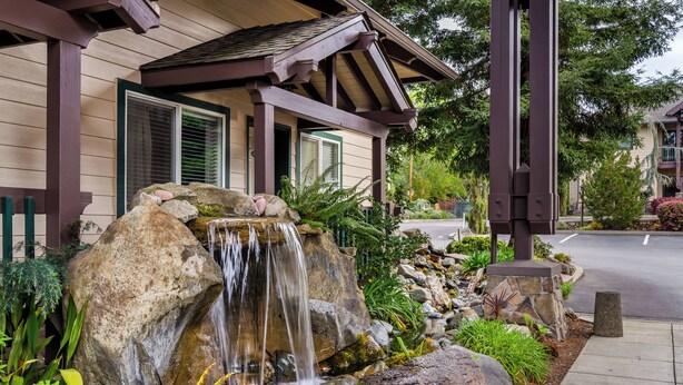 A house with a waterfall feature in the garden, a covered porch, and a street view. - Redwood Garden Inn (Grants Pass)