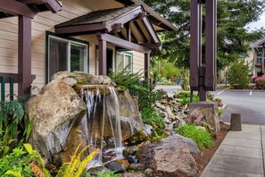 A house with a waterfall feature in the garden, a covered porch, and a street view. - Redwood Garden Inn (Grants Pass)