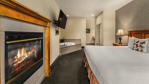 A hotel room with a fireplace, a bed, a television, a bathroom, and a nightstand. - Redwood Garden Inn (Grants Pass)