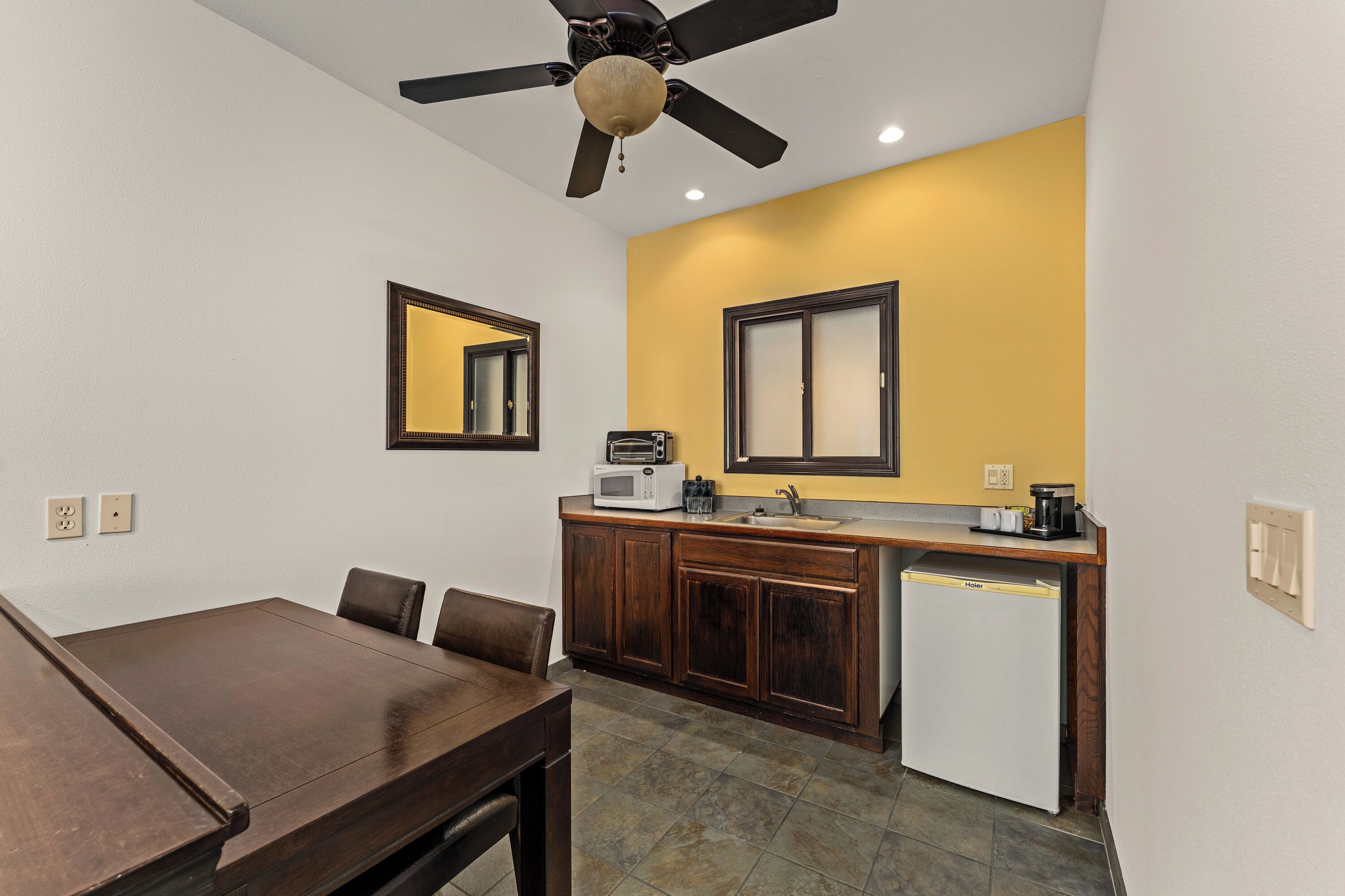 Una cocina compacta con comedor, ventilador de techo y microondas.