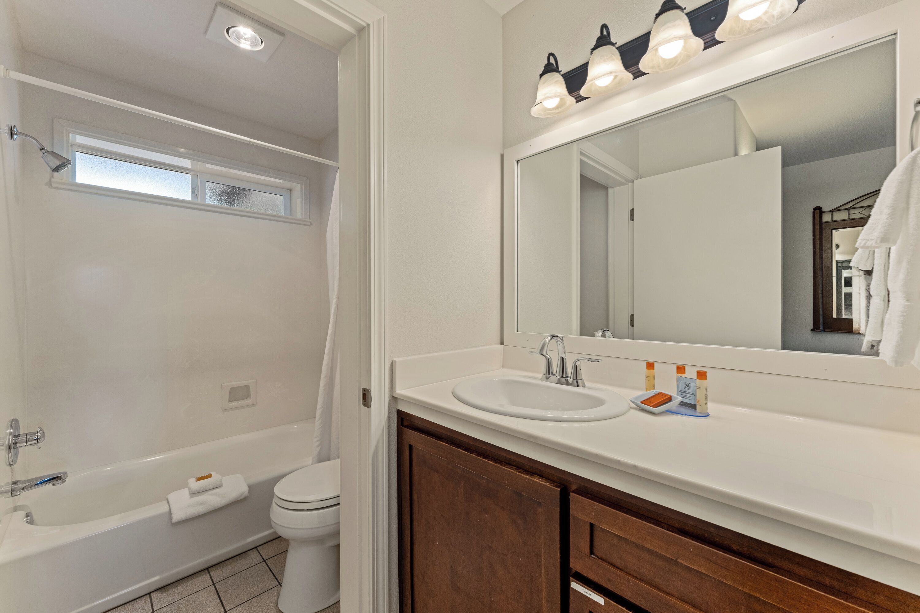 A bathroom with a bathtub, toilet, sink, and mirror.