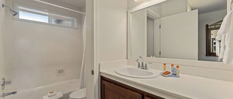 A bathroom with a bathtub, toilet, sink, and mirror.