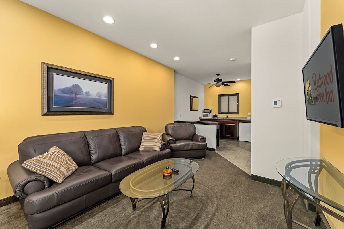 A living room with a brown leather sofa, a glass coffee table, and a framed picture on the wall.