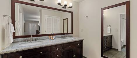 A bathroom with a double sink vanity, a large mirror, and a wall-mounted light fixture.