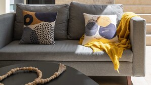 A modern living room with a grey sofa, patterned cushions, and a yellow throw blanket. - Meso Maya (Tulum)