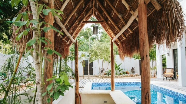 A covered outdoor area with a pool, wooden benches, and a thatched roof structure. - Enjoy space and privacy Casa Roo by BRM (Tulum)