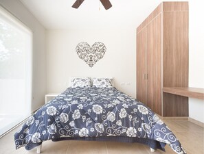 Un dormitorio con una cama, un armario y una decoración de corazón en la pared.