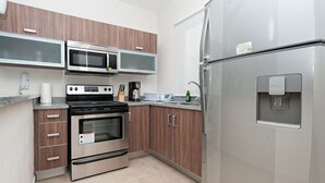 A modern kitchen with stainless steel appliances, wooden cabinets, and a built-in water dispenser. - Prana 212 by BRM (Tulum)