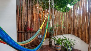 Un hamac, des plantes en pot et une clôture en bois dans une pièce.