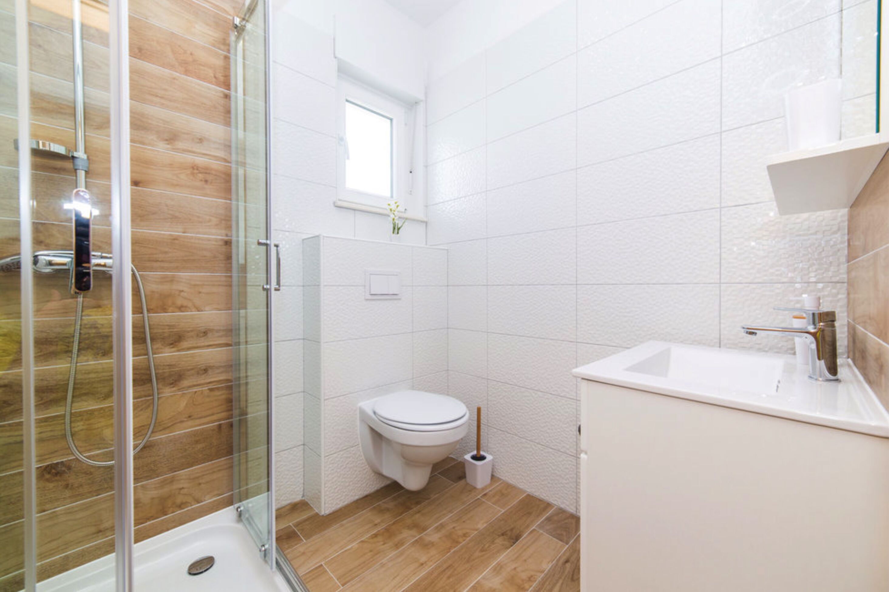 A modern bathroom with a glass shower enclosure, a toilet, and a sink.