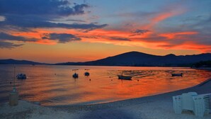 A sunset over a calm body of water with boats and a beach in the foreground. - Holiday Home Goldy Trogir-Čiovo (Trogir)