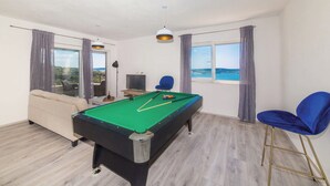 A room with a pool table, a sofa, a chair, and a TV. - Holiday Home Goldy Trogir-Čiovo (Trogir)