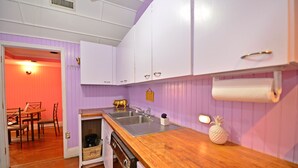 A kitchen with white cabinets, a wooden countertop, and a pineapple decoration. - Historic Apartment in the Center of Christiansted (Christiansted)
