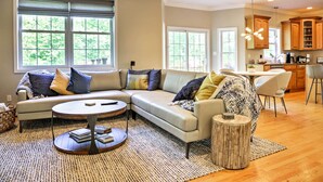 A spacious living room with a sectional sofa, a coffee table, and a dining area with a kitchen in the background. - Colonial-Style 'Warwick Retreat' - 1 Hour to NYC! (Monroe)