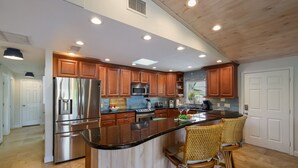 Une cuisine moderne avec des meubles en bois, des appareils en acier inoxydable et un îlot central doté de tabourets de bar.