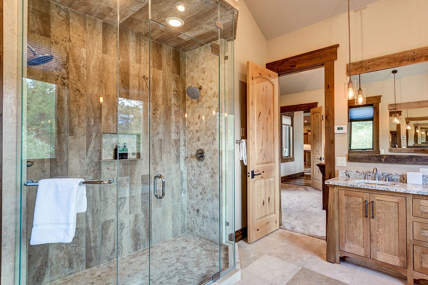A modern bathroom with a glass-enclosed shower, wooden cabinets, and a large mirror.