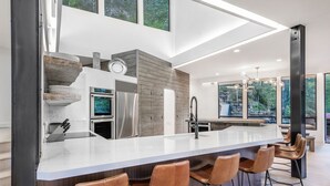 Een moderne keuken met een groot eiland, roestvrijstalen apparatuur en een wand met stenen accenten.